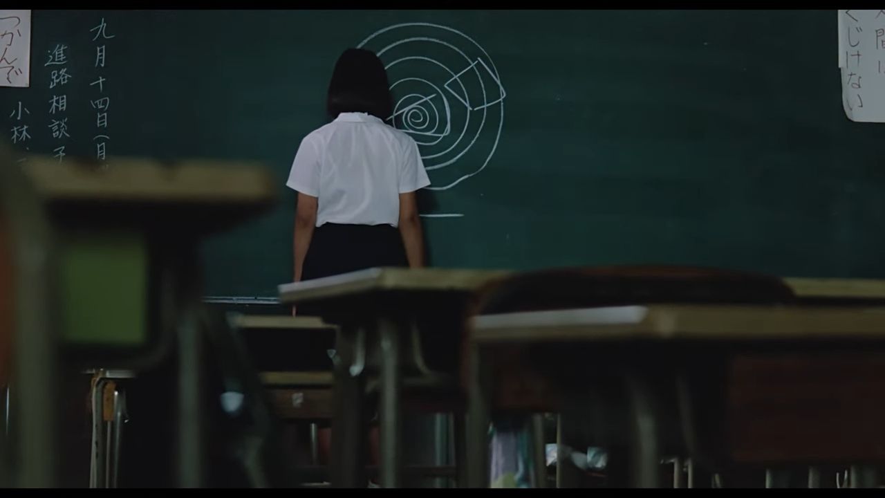 girl standing at blackboard drawing typhoon in chalk