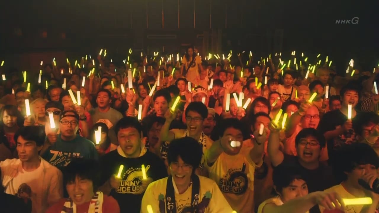 woman is hoisted above giant crowd of fans holding yellow glowsticks