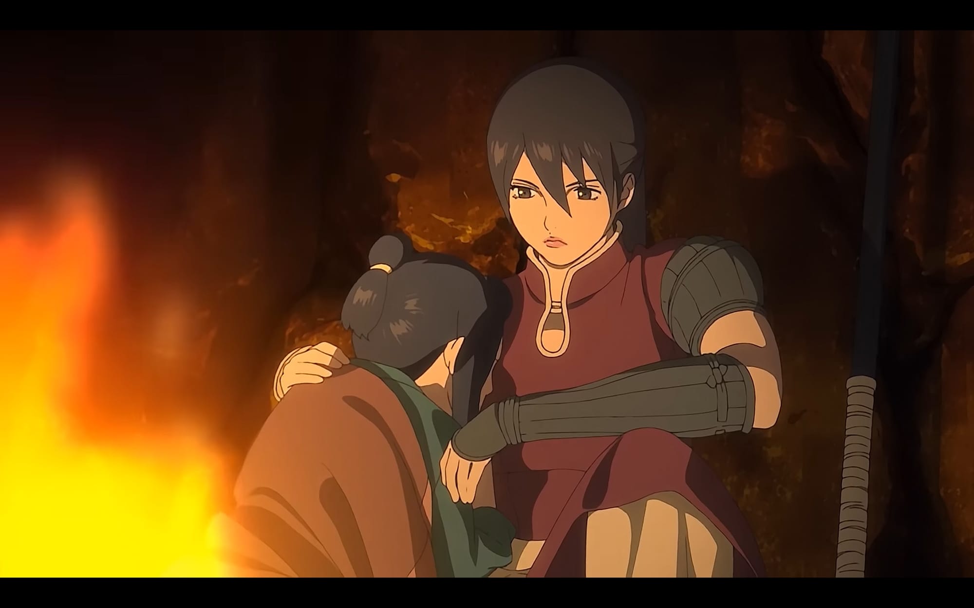 balsa sits with chagum, a young crying boy covered by a blanket, next to a fire
