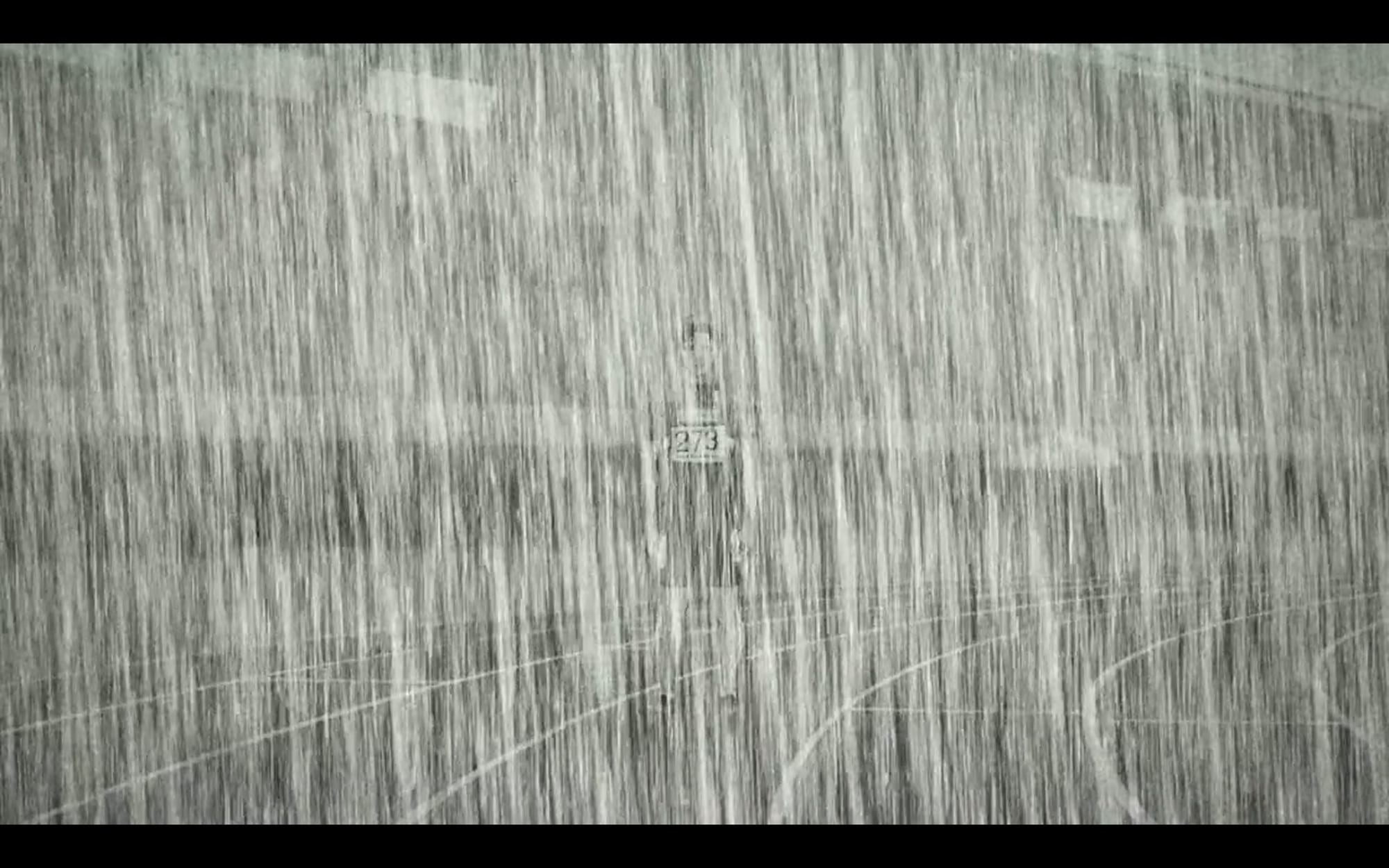 A man stands on a track as rain pours down. His uniform reads, "273."